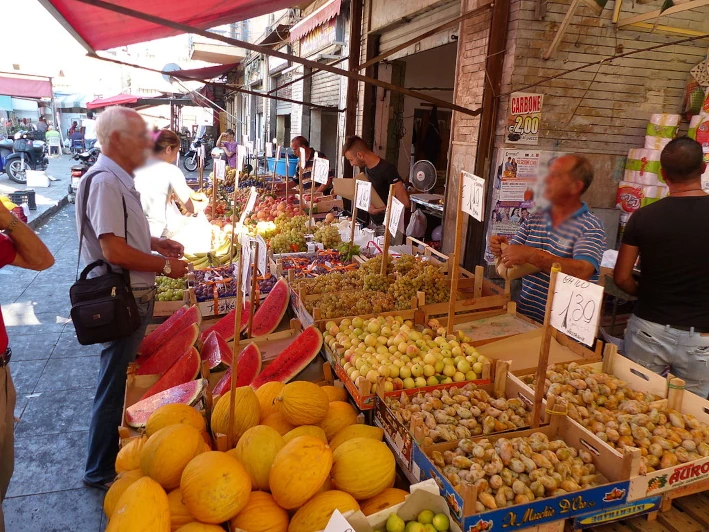 Ein Händler im Gespräch mit einem Touristen auf dem Markt Ballarò