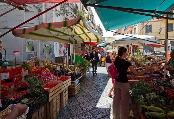 Eine Frau steht an einem Stand auf einem Markt in Palermo