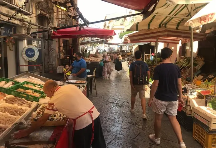 Mann ordnet auf dem Mercato Del Capo an einem Fischstand die Auslage