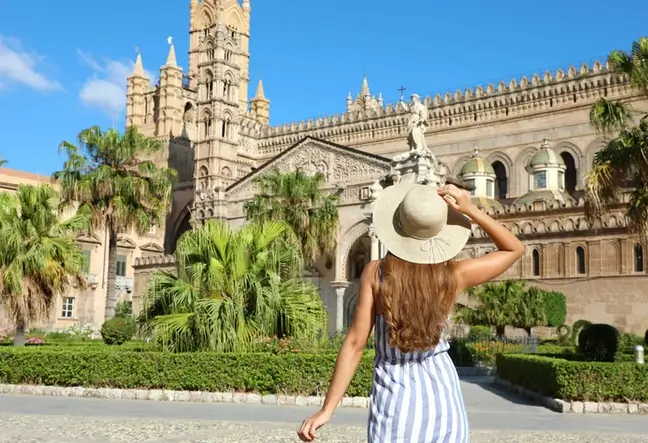 Eine junge Frau steht vor der Kathedrale in Palermo